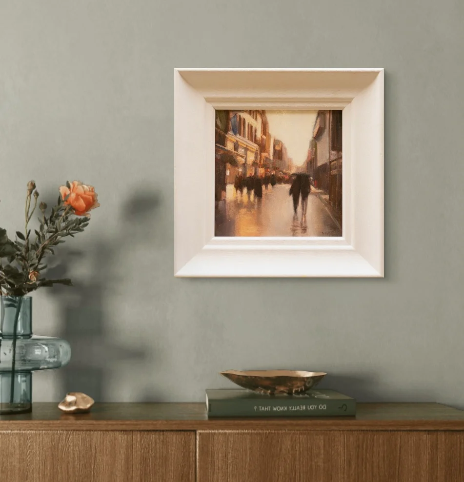 Rainy day Henry Street Dublin oil painting  — warm streetlights and reflections on wet pavement, framed in a bedroom setting, by Deirdre Hayes.