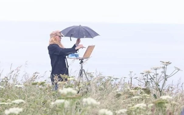 Irish plein air artist Deirdre Hayes painting on location along the Irish coastline, creating atmospheric outdoor landscape studies.