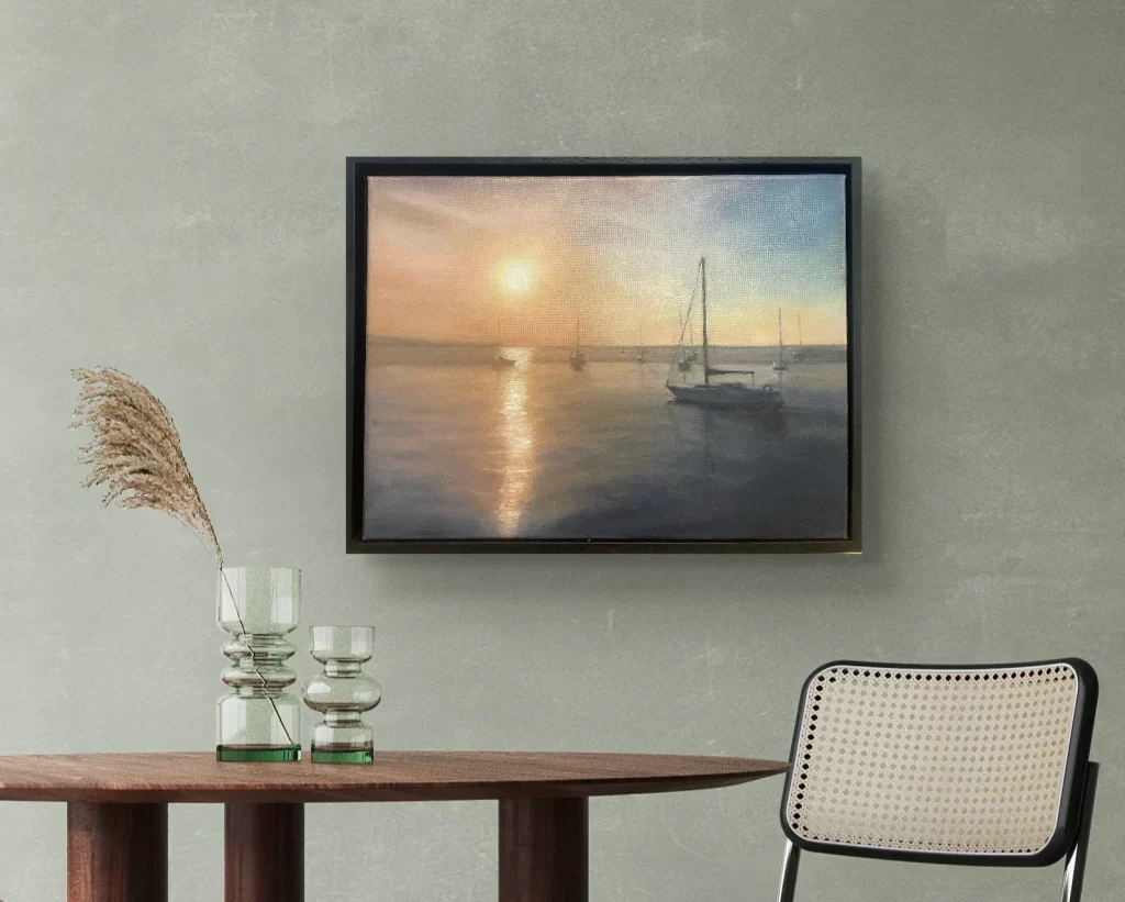 Dublin Bay Sunset — sailboats on calm water under a glowing evening sky, framed on a sage-green wall, by Deirdre Hayes.