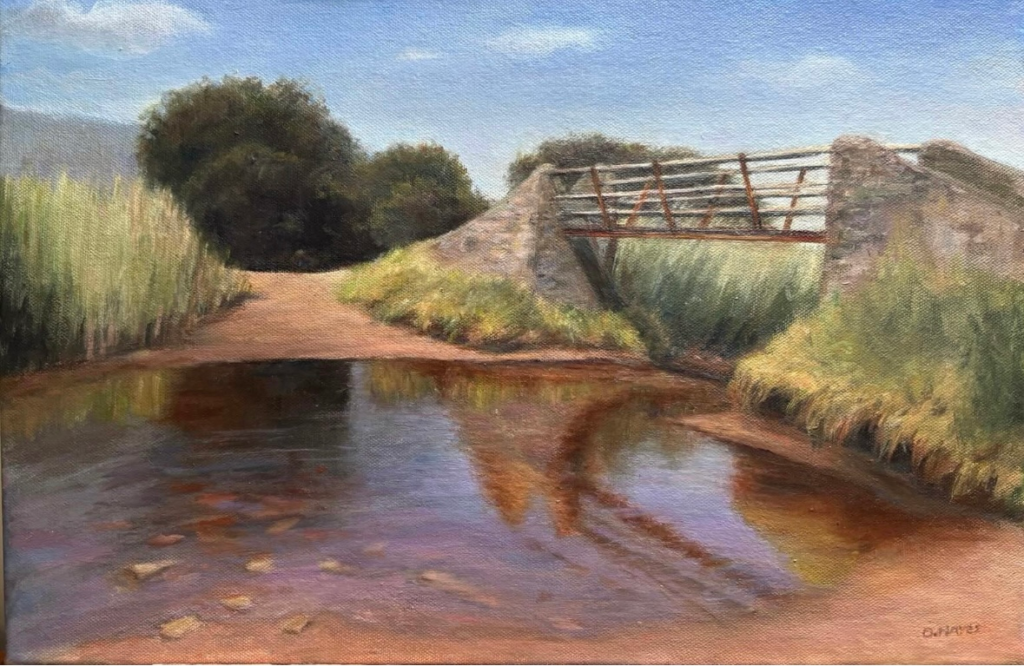 Commissioned oil painting of a stone footbridge crossing a shallow stream in Castlegregory, County Kerry, with reeds, reflections, and a bright summer sky.